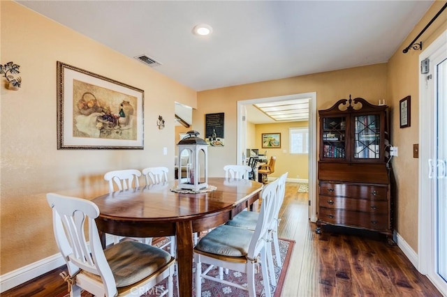 dining space with dark wood-style floors, visible vents, and baseboards