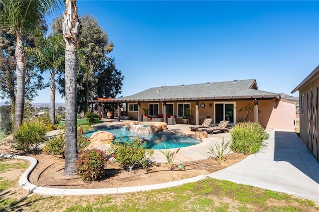 rear view of property featuring stucco siding, an outdoor pool, and a patio