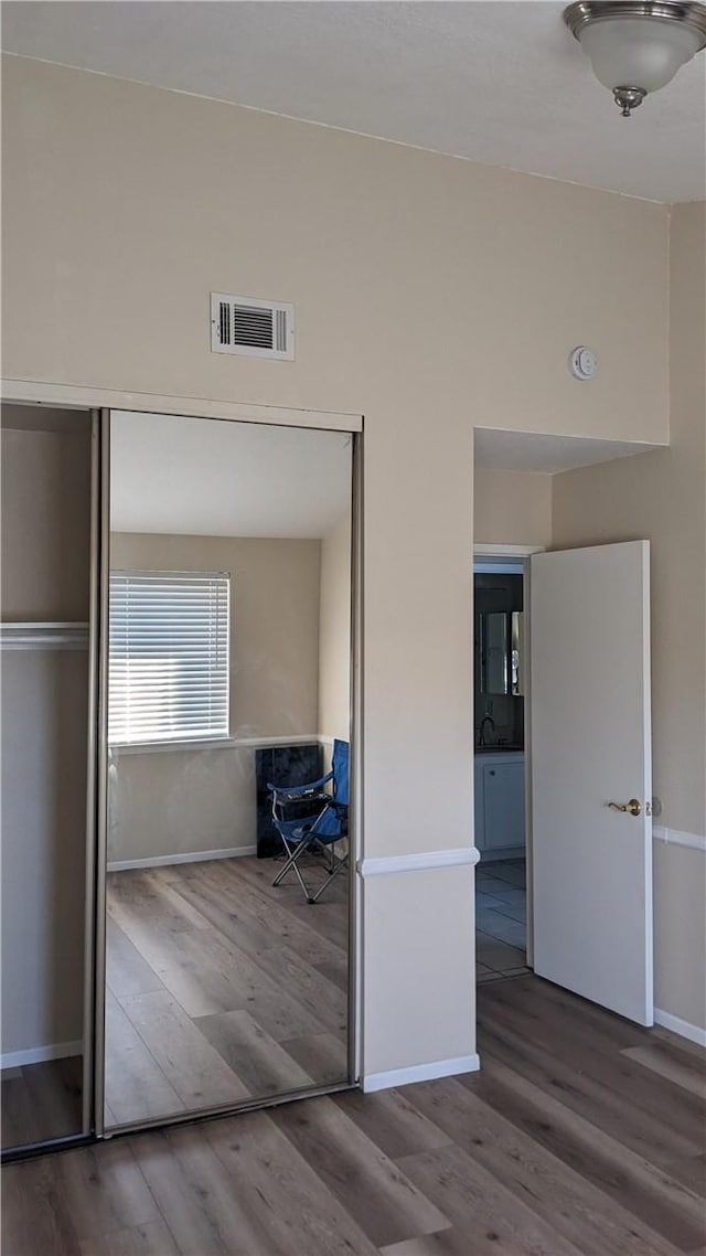 unfurnished bedroom featuring wood-type flooring, sink, and a closet