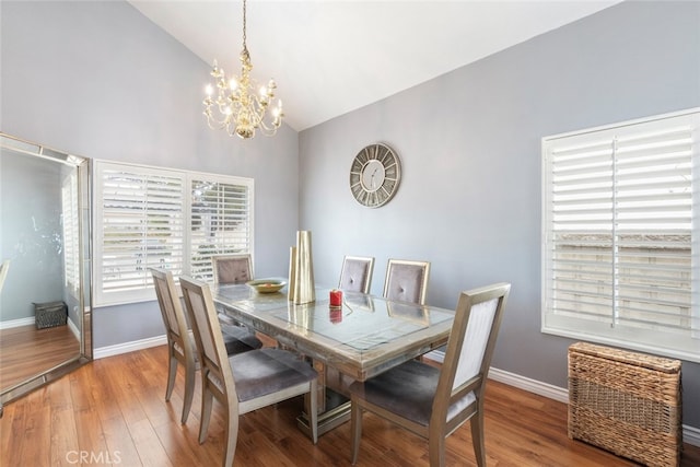 dining area with an inviting chandelier, wood-type flooring, and lofted ceiling