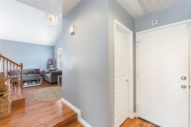 foyer entrance with vaulted ceiling and light hardwood / wood-style floors