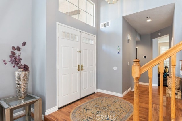 entrance foyer with hardwood / wood-style flooring and a towering ceiling