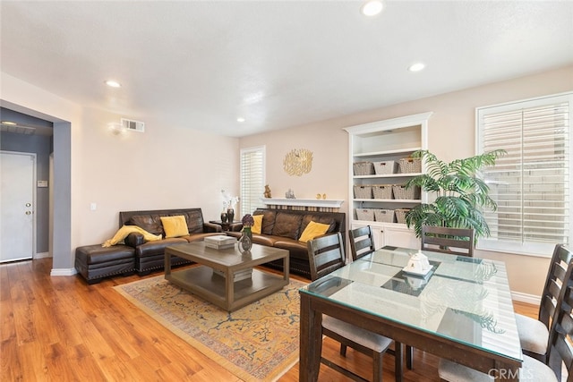 living room featuring light wood-type flooring, a wealth of natural light, and built in features