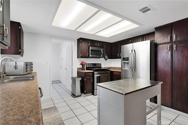 kitchen featuring sink, dark brown cabinets, stainless steel appliances, and light tile patterned flooring