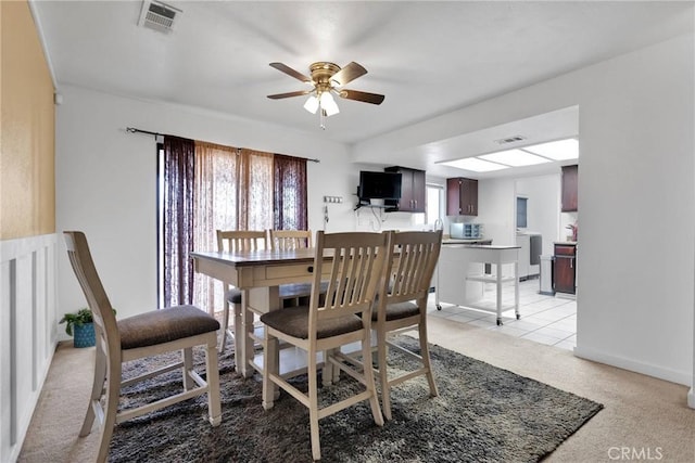 dining area with ceiling fan and light carpet