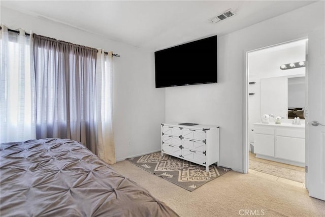 carpeted bedroom with multiple windows, sink, and ensuite bath