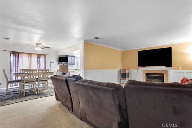 living room featuring light carpet, ornamental molding, and ceiling fan