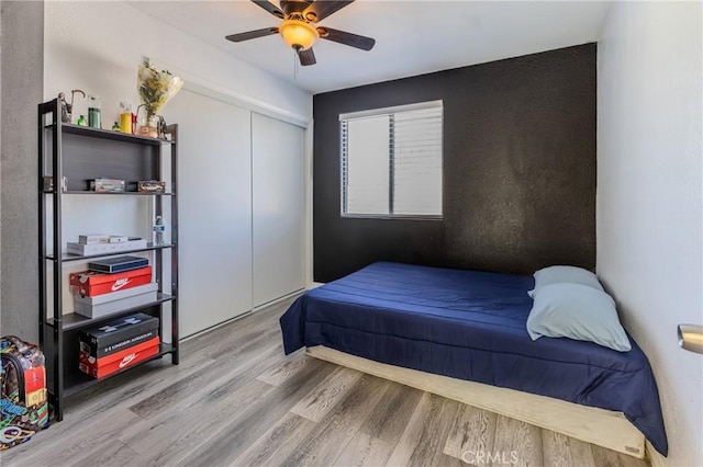 bedroom with ceiling fan, light hardwood / wood-style floors, and a closet