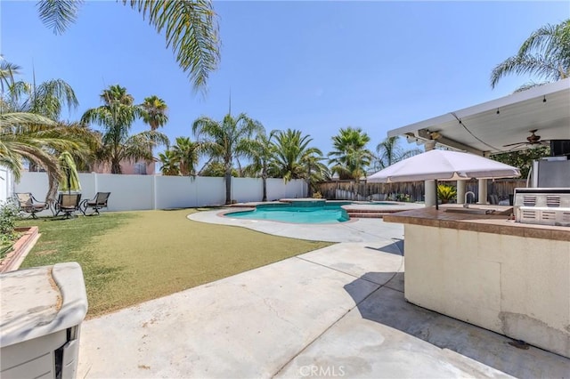 view of swimming pool featuring a lawn, exterior bar, exterior kitchen, ceiling fan, and a patio area