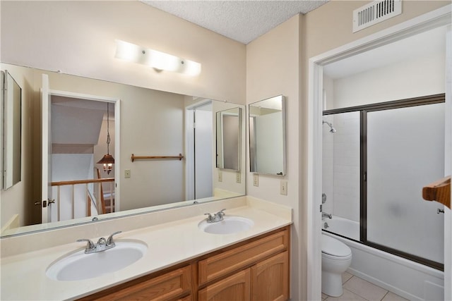 full bathroom featuring shower / bath combination with glass door, vanity, toilet, tile patterned floors, and a textured ceiling