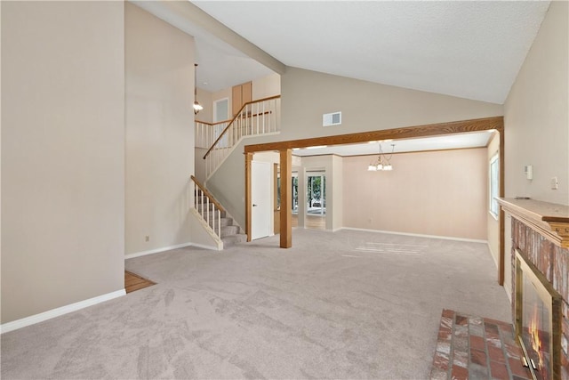 unfurnished living room featuring high vaulted ceiling, carpet flooring, and a chandelier