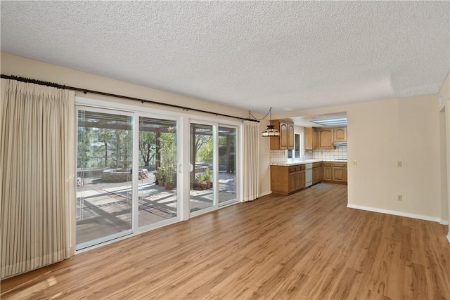 unfurnished living room with light hardwood / wood-style flooring and a textured ceiling