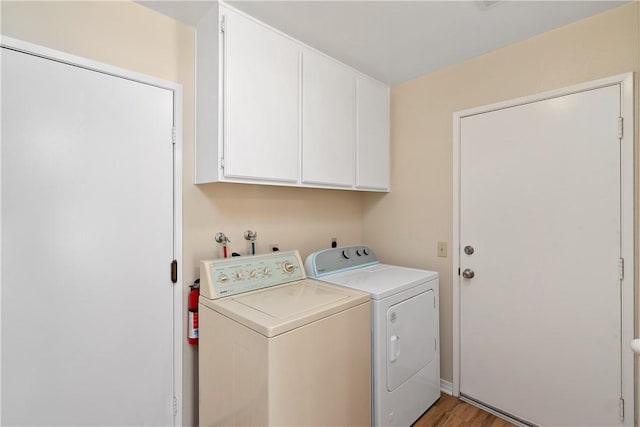 laundry area featuring cabinets, wood-type flooring, and separate washer and dryer