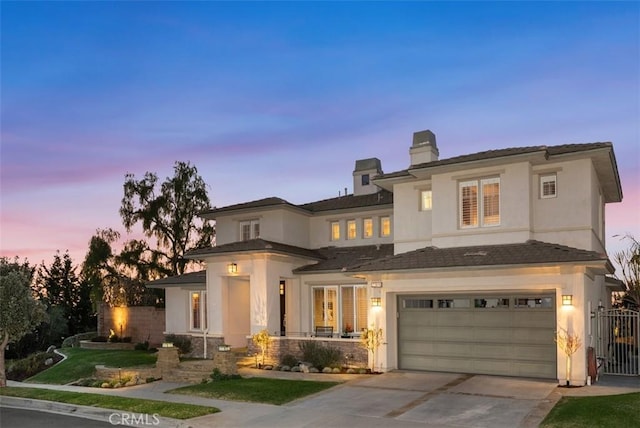 view of front of home featuring stucco siding, an attached garage, concrete driveway, and fence