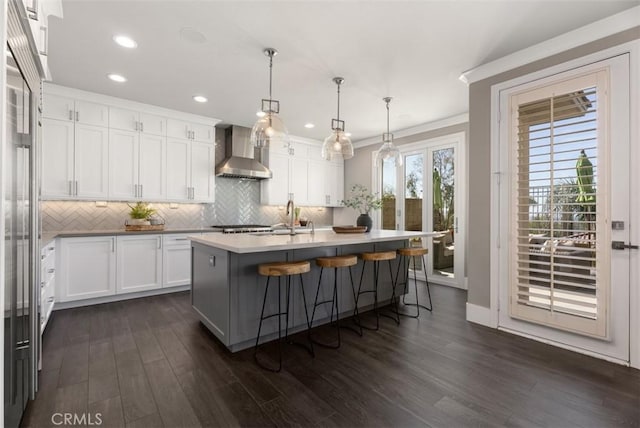 kitchen featuring a sink, dark wood-type flooring, white cabinetry, wall chimney exhaust hood, and backsplash