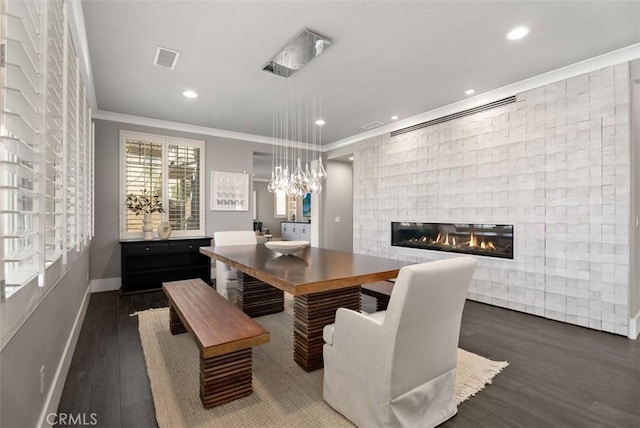 dining area featuring visible vents, ornamental molding, wood finished floors, a stone fireplace, and baseboards