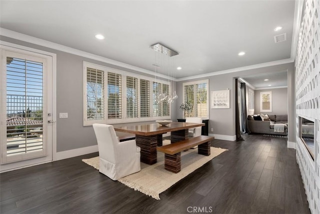 dining area featuring crown molding, visible vents, dark wood-style flooring, and a large fireplace