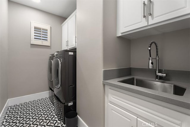 laundry area with baseboards, cabinet space, separate washer and dryer, a sink, and tile patterned floors