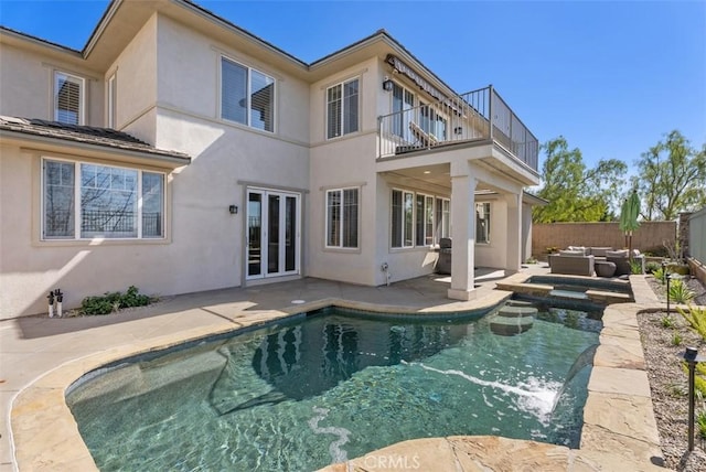 back of house with a balcony, fence, stucco siding, french doors, and a patio area