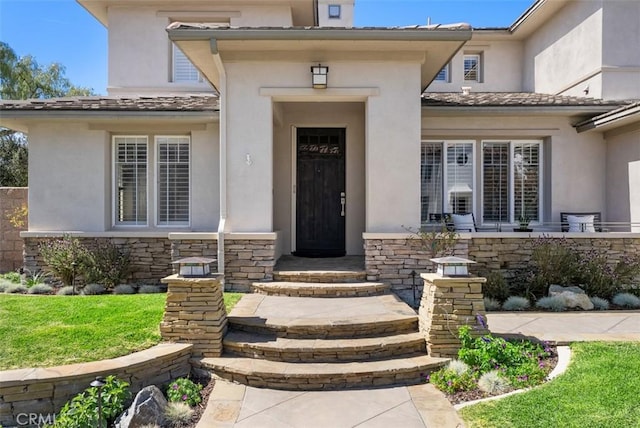 view of exterior entry with stone siding and stucco siding