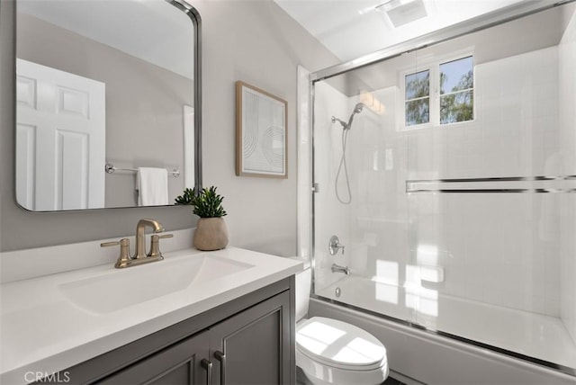 bathroom featuring combined bath / shower with glass door, toilet, and vanity