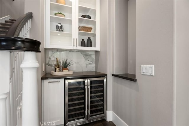 bar featuring baseboards, backsplash, beverage cooler, and a bar