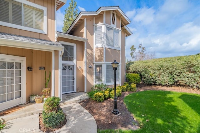 doorway to property featuring board and batten siding and a lawn