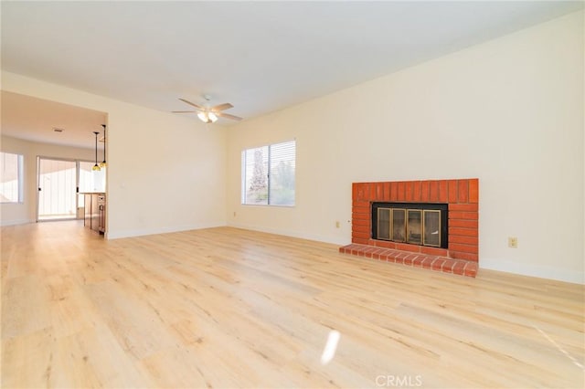 unfurnished living room with a brick fireplace, plenty of natural light, and light hardwood / wood-style floors