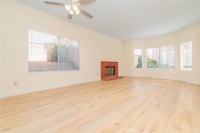 unfurnished living room with a brick fireplace, light hardwood / wood-style floors, and ceiling fan