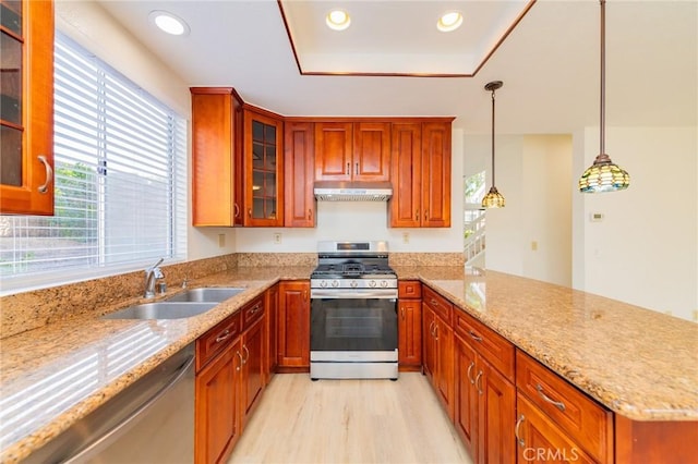 kitchen featuring light stone counters, sink, stainless steel appliances, and hanging light fixtures