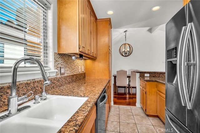 kitchen with sink, light tile patterned floors, dark stone countertops, backsplash, and stainless steel appliances