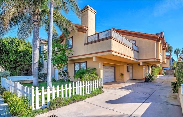 view of front of property with a fenced front yard, a balcony, a garage, concrete driveway, and stucco siding