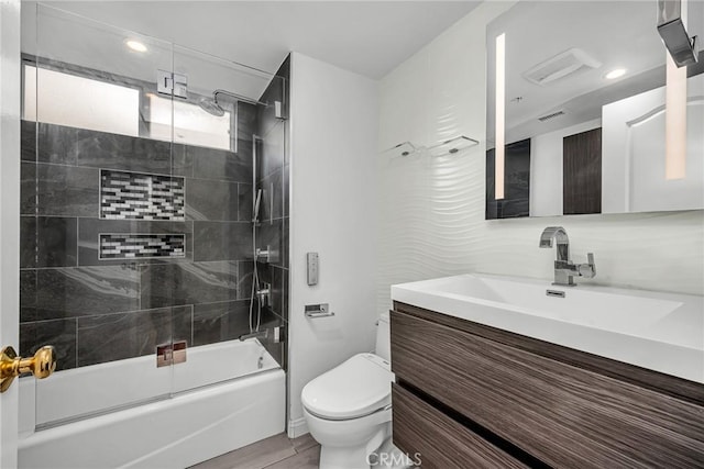 full bathroom featuring vanity, decorative backsplash, combined bath / shower with glass door, and toilet