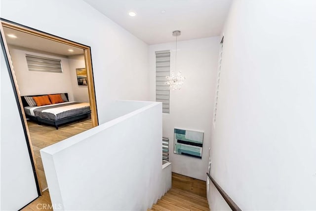 staircase featuring hardwood / wood-style flooring, heating unit, and an inviting chandelier