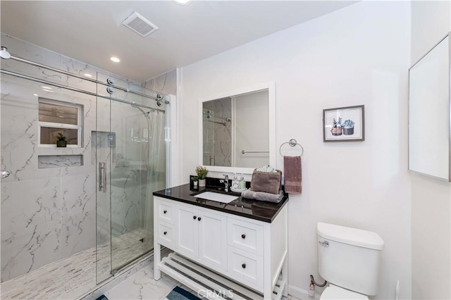 bathroom featuring a shower with door, vanity, and toilet