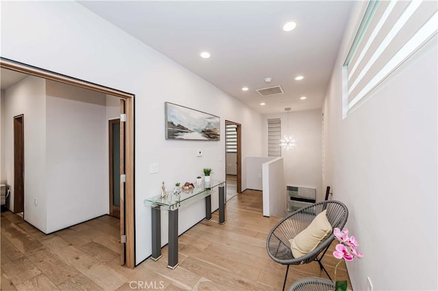 hall featuring a chandelier and light hardwood / wood-style flooring