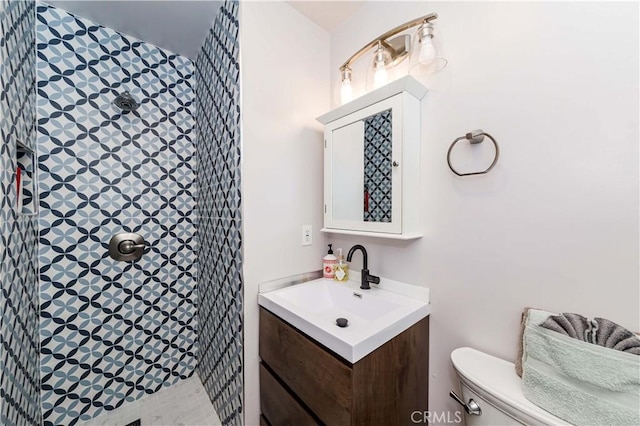 bathroom featuring vanity, toilet, and a tile shower