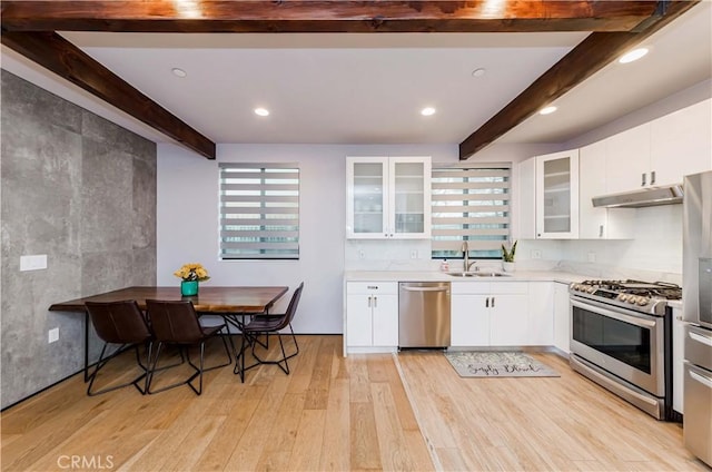 kitchen with sink, white cabinetry, appliances with stainless steel finishes, beam ceiling, and light hardwood / wood-style floors