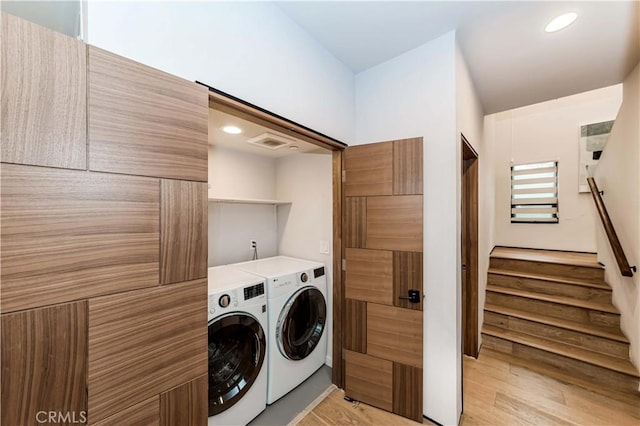 laundry room with washing machine and dryer and light hardwood / wood-style floors