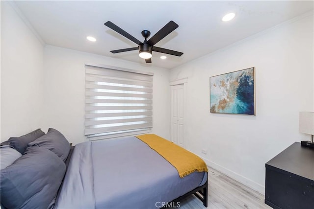 bedroom featuring ornamental molding, ceiling fan, light wood-type flooring, and a closet