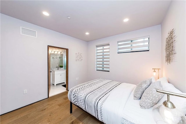 bedroom with sink, light hardwood / wood-style floors, and ensuite bath