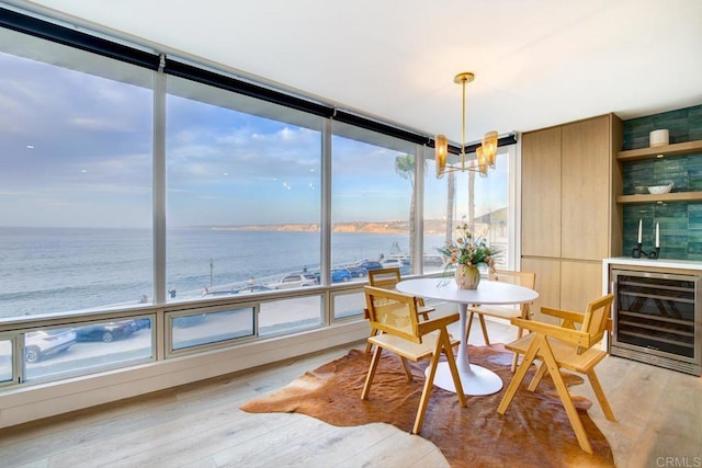 dining space featuring a water view, light hardwood / wood-style floors, and wine cooler