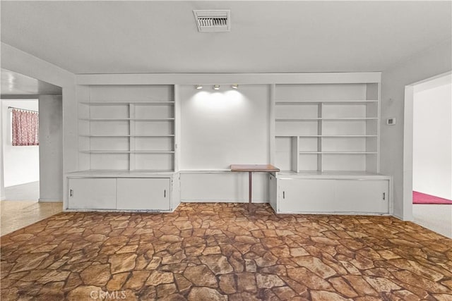 unfurnished living room featuring built in shelves