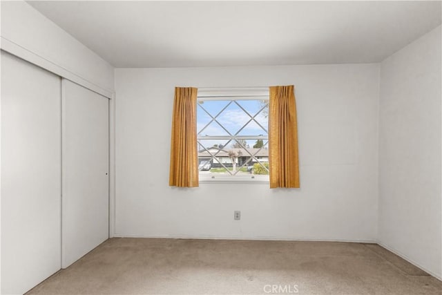 unfurnished bedroom featuring light colored carpet and a closet