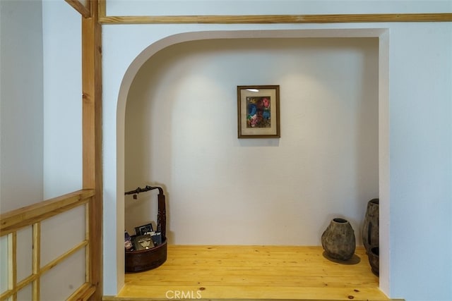 corridor with wood finished floors and arched walkways