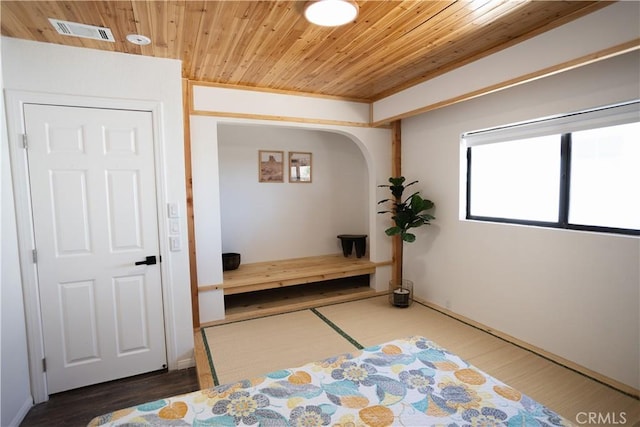 bedroom with wood finished floors, wooden ceiling, visible vents, and arched walkways