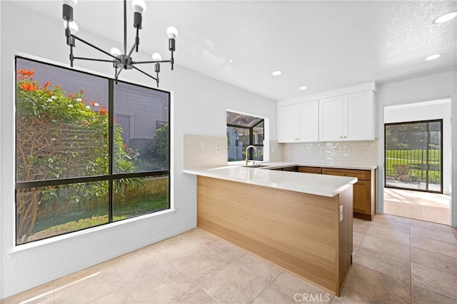 kitchen with light countertops, a sink, white cabinets, and decorative backsplash