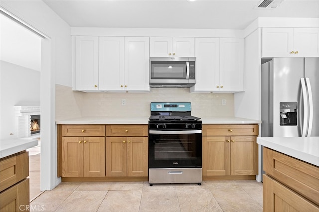 kitchen with appliances with stainless steel finishes, light countertops, white cabinetry, and tasteful backsplash