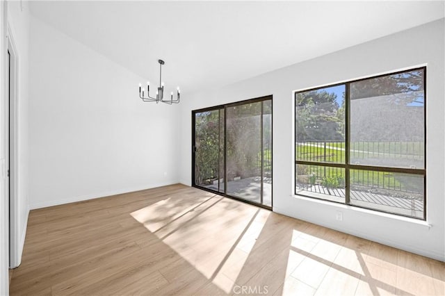 unfurnished dining area featuring lofted ceiling, a notable chandelier, baseboards, and wood finished floors