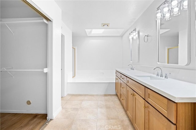 bathroom with double vanity, a skylight, tile patterned flooring, and a sink